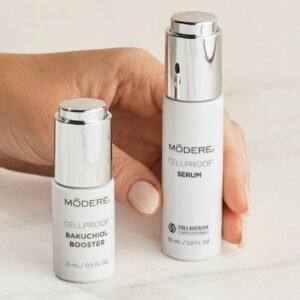 Two white skincare bottles with silver caps held by a hand, labeled Bakuchiol Booster and Cellproof Serum from Mödere.