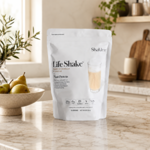 Life Shake Plant Protein powder in a white resealable bag on a marble kitchen island with a bowl of pears nearby.