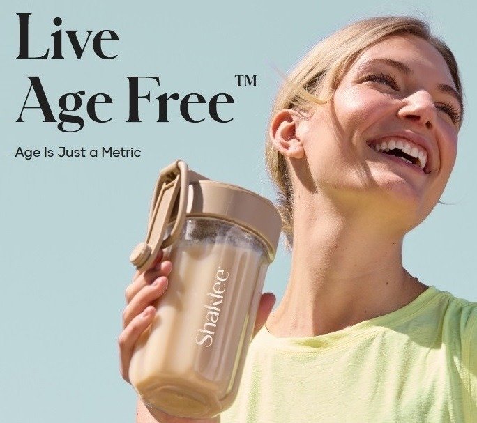 Smiling woman outdoors holding a beige shaker bottle with a pale blue sky background; visible slogan reads 'Live Age Free' and 'Age Is Just a Metric'.